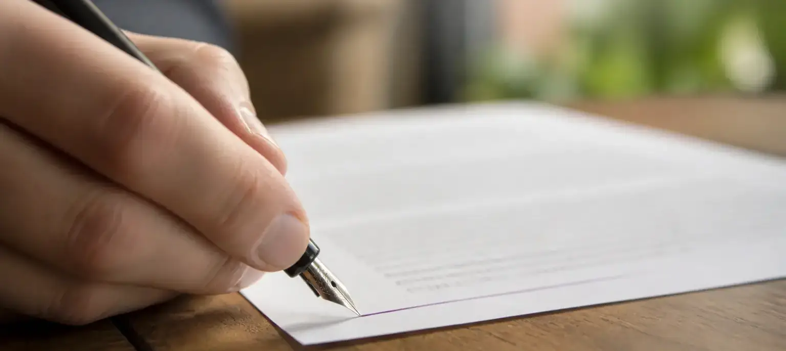 Une plume à l’encre violette ajoute une ligne au bas d’une page imprimée