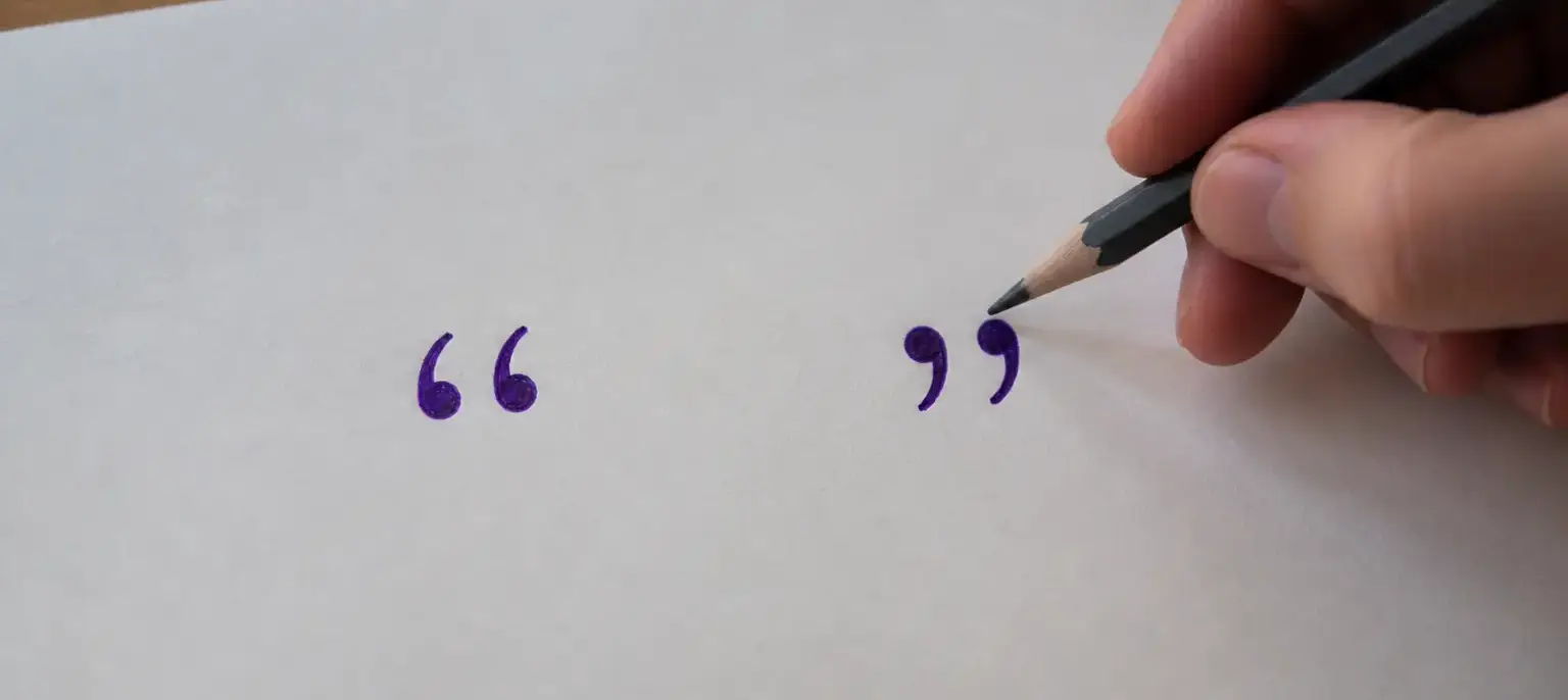 Un crayon et une feuille portant des guillemets français tracés à l’encre violette