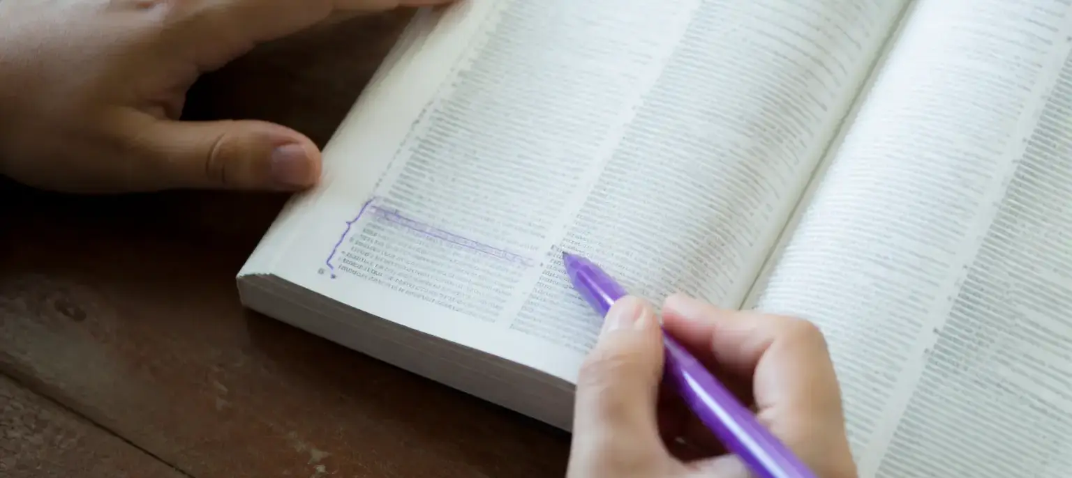 Un dictionnaire ouvert, une expression soulignée à l’encre violette dans la marge