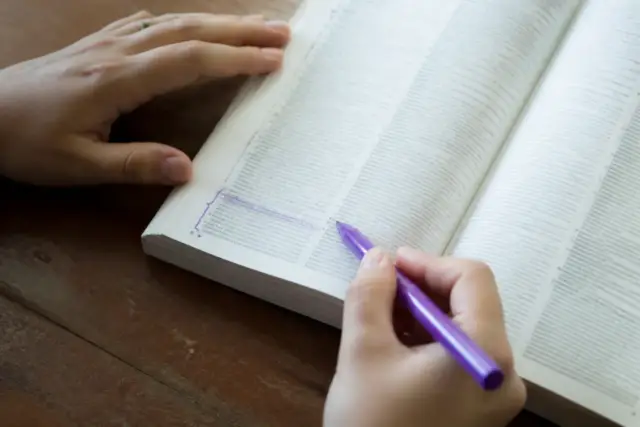 Un dictionnaire ouvert, une expression soulignée à l’encre violette dans la marge