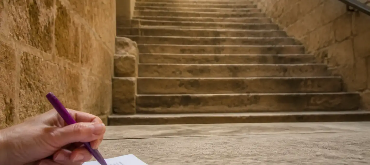 Un escalier de pierre vu d’en bas, une main annote à l’encre violette la marge d’une épreuve