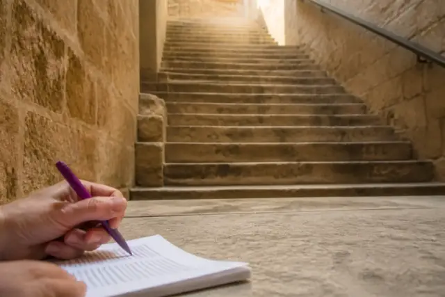 Un escalier de pierre vu d’en bas, une main annote à l’encre violette la marge d’une épreuve