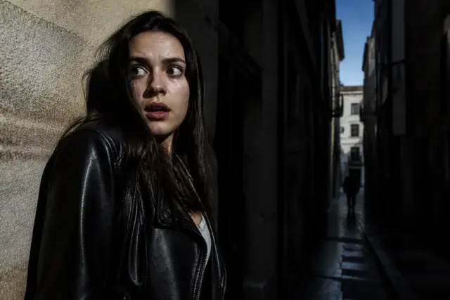Femme effrayée dans une ruelle sombre évoquant un synonyme de peur palpable